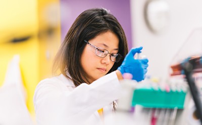 一名实验室工作人员正在工作台前进行移液操作。