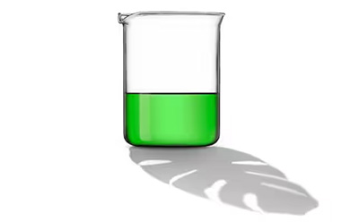 Glass beaker containing bright green liquid, casting a shadow on a white surface.