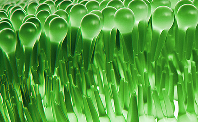Close-up of glossy green, droplet-shaped structures arranged in dense rows, resembling a stylized microscopic surface.