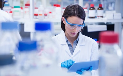 Analytic Chemistry 化学家戴着安全眼镜,使用平板电脑在实验室测试冠状病毒 Covid19 疫苗。