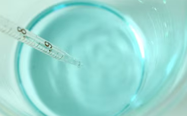 Biological Buffer Light blue biological buffer solution in beaker with pipette.