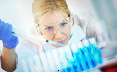 High purity Biochemicals & reagents Scientist wearing safety goggles examines blue liquid samples in test tubes in a laboratory.