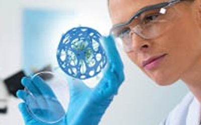化学生物学工具 一位身穿白大褂、戴着蓝色手套的科学家正在检查一个详细的蓝色分子结构三维模型,背景是模糊的实验室设备。