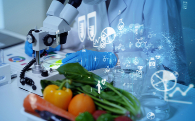A laboratory setting with a focus on food science and analysis, featuring a person in lab coat and gloves handling test tubes near fresh vegetables with digital graphics of molecular structures and data overlaid.