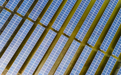 PSC in energy Top-down view of a floating photovoltaic array consisting of modular solar panels arranged in parallel rows on a water body, illustrating large-scale renewable energy deployment.