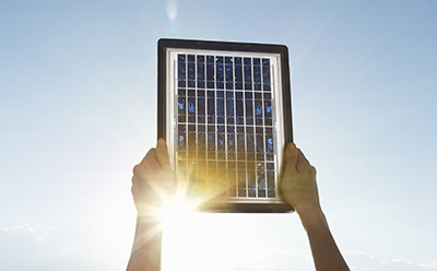 Small solar panel A person holding up a small solar panel against a bright sun.