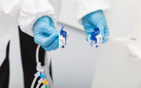 NovaSeptum® SURe sterile sampling assembly with AseptiQuik® S connector 戴着蓝色手套的手正在操作小型电气连接器。操作者身着白色实验服,暗示其处于专业或实验室环境中。连接器上连接有彩色电线。