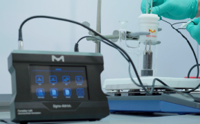 A close-up of a laboratory setup featuring a digital device with a touchscreen interface labeled "Sigma 400," connected to a scientific apparatus. A gloved hand is manipulating the equipment in the background.