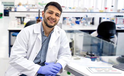 <p>Transforming Pharma Operations with Generative AI: From Data Silos to Intelligent Insights</p>
A scientist in a lab coat and gloves sits at a lab bench with various equipment in the background.