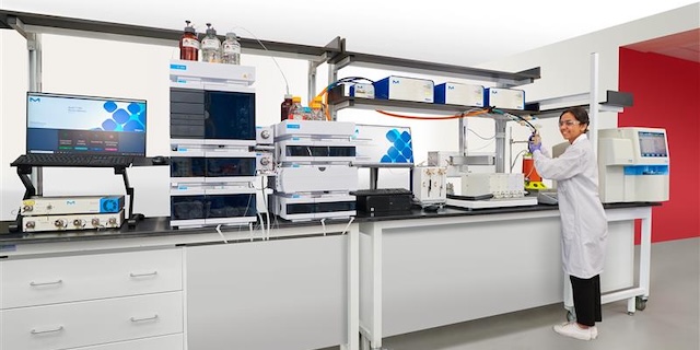 <p>在灌注细胞培养过程中启用糖基化监测</p> A laboratory setting featuring advanced scientific equipment, including multiple chromatography systems and a computer monitor displaying data. A researcher in a lab coat is actively engaged in an experiment at a workbench, surrounded by various instruments and supplies essential for laboratory analysis.