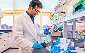 Custom Assay Development Services Scientist in a lab coat working at a laboratory bench, surrounded by various laboratory equipment and materials.