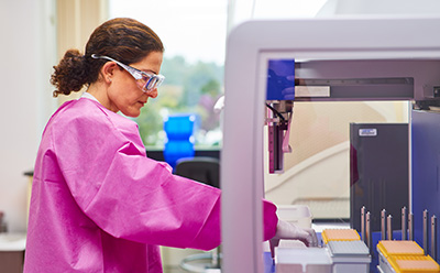 Preclinical Evaluation Scientist placing a microplate on an automated workstation.
