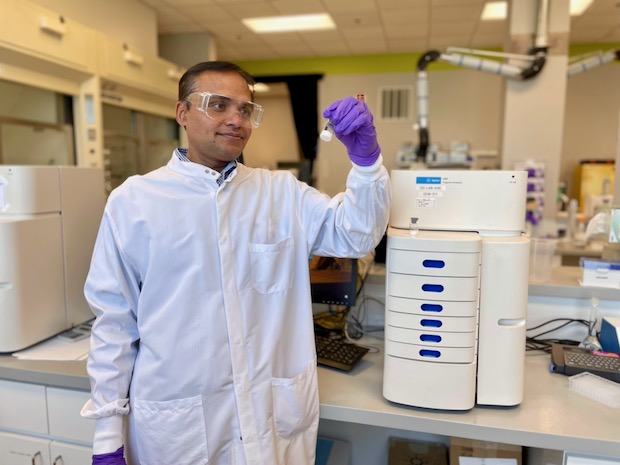 Mahesh lab Karwa正站在实验室内的一台mRNA纯度测定分析仪器旁。