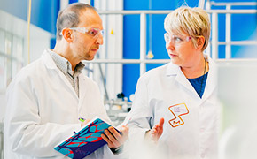 Scientists in the M Lab™ One scientist explaining new innovation to another scientist in front of a blue window.