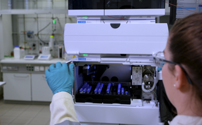 Clinical Lipids CDMO Services Lab scientist is loading analytical samples into a High-Performance Liquid Chromatography (HPLC) machine for monitoring the progress of chemical syntheses and ensuring the quality of the produced materials.
