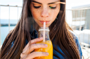 Juice testing for food safety 一位女士正用吸管喝橙汁