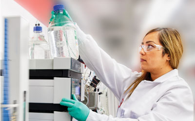 Purification of DNA and RNA oligos Female researcher in lab coat and gloves operating an HPLC during analysis of oligos