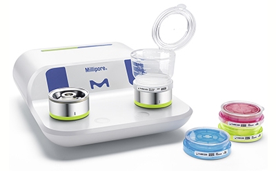 Milliflex® Quantum 快速检测系统 一个密理博微生物过滤系统,上面有两个过滤装置,前面有三个培养皿,里面有培养的样品。该系统为白色和蓝色相间,带有密理博徽标。培养皿中装有彩色培养基:一个蓝色,一个粉色,一个黄色。