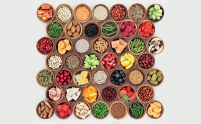 a top-down view of a neatly arranged grid of small wooden bowls, each containing different natural food ingredients.