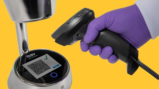 <p>为未来空气监测做好准备</p> A close-up image of a hand wearing a purple glove holding a barcode scanner aimed at a circular device displaying a QR code. The background is a vibrant blue, enhancing the focus on the scanning action and the technology being used.