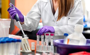 从工作台到批量生产的生物缓冲剂 身着白大褂,戴着安全手套和安全护目镜,在实验室工作的女性。