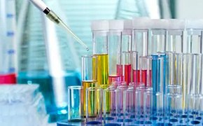 A laboratory setup showcasing a series of test tubes filled with various colored solutions, highlighting the use of biomedical polymers for drug delivery applications, with a pipette adding a drop of liquid to one of the tubes.