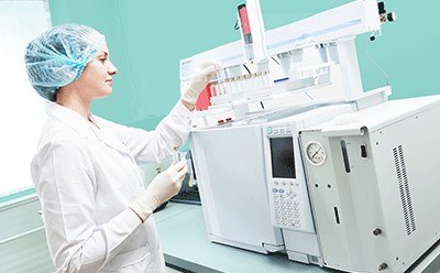 Scientist placing a vial flask into a gas chromatography instrument.