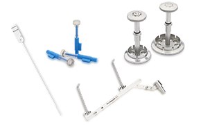 白色背景上整齐摆放着一系列医疗器械，包括注射器和其他工具。可见的有一种细长的器械，末端有一个环，两种类型的注射器--一种是蓝色的活塞，另一种是结构复杂的注射器--还有一些金属器械，似乎是专门用于医疗程序的仪器的一部分。还有一种金属器械，其设计棱角分明，末端有一个类似夹子的特征，暗示其可用于精确的医疗任务。