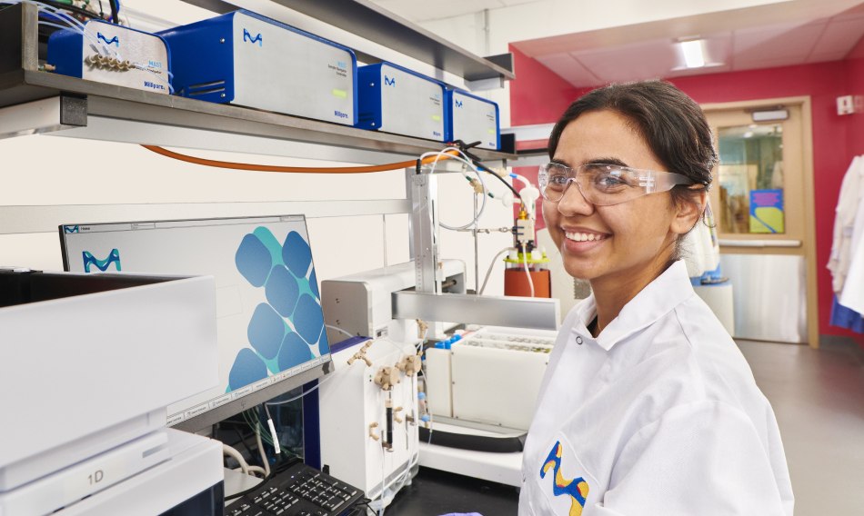 Scientist  wearing safety glasses standing in front of a lab bench with MAST® Autosampling Solution.
