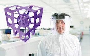 Person in a lab coat by a purple 3D-printed structure against a bright, clean background.