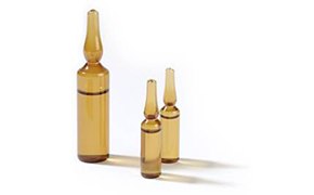 Two small brown glass vials and one large brown glass vial cast shadows on a white background.