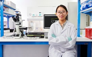 科学家站在Luminex®仪器旁，手持一盒MILLIPLEX®多重生物标志物测定试剂，背景工作台上放着一台SMCxPRO®超灵敏免疫分析仪