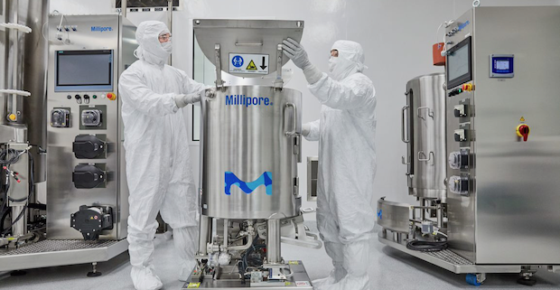 Researchers work in a GMP setting wearing full safety suits, masks and eye protection