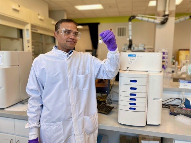 Karwa stands in lab next to an analytical instrument that helps determine the purity of mRNA.