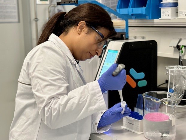 Aditi wears PPE and uses a pipette to extract a solution in the lab.