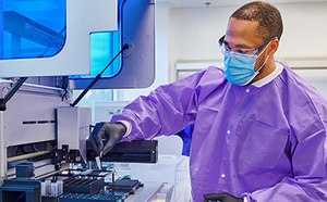 身穿防护服的男性实验室技术人员正使用机器进行某些测试。