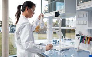 在明亮整洁的现代实验室环境，身着白大褂的女科学家正用Q-POD取水臂将超纯水注入容量瓶