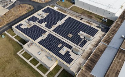 Aerial view of a manufacturing building with a large rooftop solar array, illustrating site‑level electrification and low‑carbon energy projects.