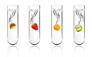 四支装满水的透明试管。每支试管中都放入了不同的水果，水果落入液体时在试管顶端溅起水花。