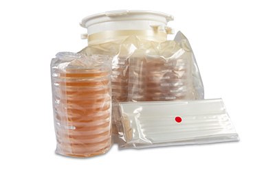 A collection of sealed bags containing various petri dishes and a flat tray, all arranged together, highlighting the sterile packaging and preparation for laboratory use.