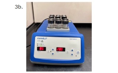 A digital heat block device labeled as "3b." The heat block is blue with a white control panel and a digital display. The display shows a temperature setting of 80°C and a time setting of 20 minutes. On top of the heat block, there are eight glass vials, each capped with a black screw cap. The vials are placed in a metallic block that holds them securely. The device is positioned on a black surface with a light-colored background.